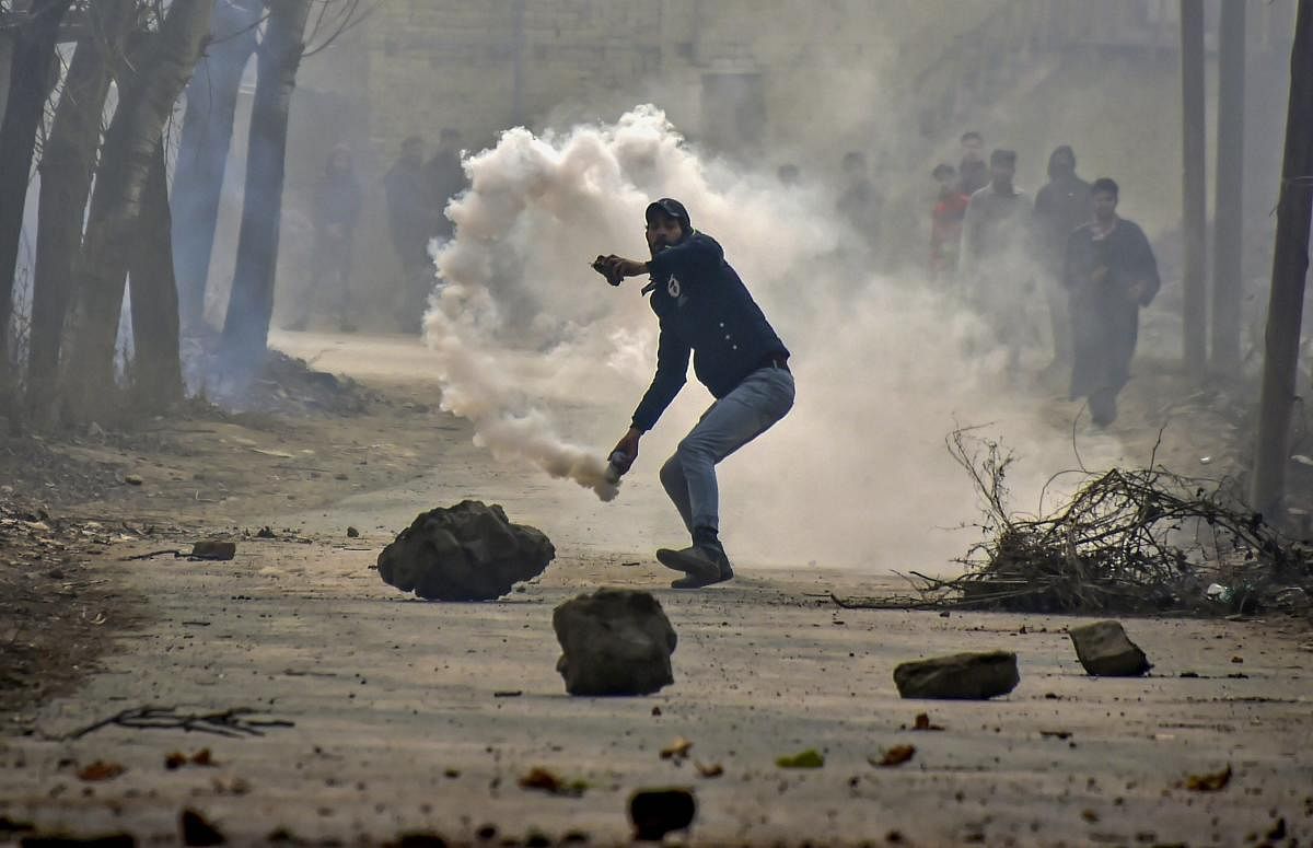 Chattergam: A protester hurls stones on security personnel near the encounter site at Kuthipora village, Chattergam in Budgam district of central Kashmir, Wednesday, Nov. 28, 2018. Two militants including most wanted Lashkar-e-Taiba militant Naveed Jhutt, who was allegedly involved in the assassination of journalist Shujaat Bukhari, were killed in the encounter. (PTI Photo/S Irfan) 