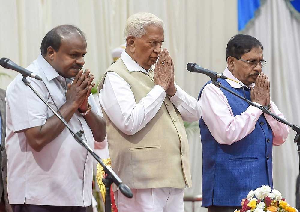 Karnataka Governor Vajubhai Vala flanked by Chief Minister HD Kumaraswamy (L) and Deputy CM G Parameswara during the swearing-in ceremony for the cabinet expansion of coalition government of Congress-JD(S), in Bengaluru. PTI Photo 