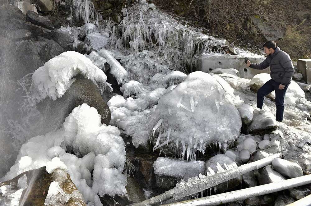  A tourist takes photos of icicles formed due to burst of a water supply line during a snowfall at Pahalgam in Anantnag district of south Kashmir. PTI Photo 