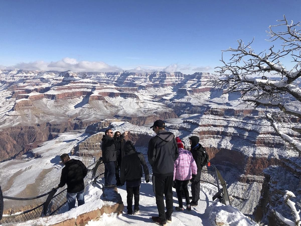 Tourists take photos of a snow-covered Grand Canyon, in Arizona. A winter storm has left snow across the American Southwest. AP/PTI