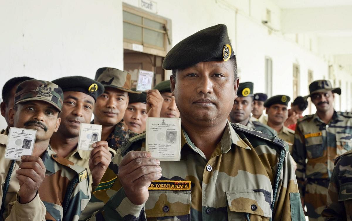 Tripura State Rifles personnel show their voter identity cards before casting their votes through postal ballots for the Lok Sabha elections, in Dharmanagar, Manday, April 8, 2019. (PTI Photo)