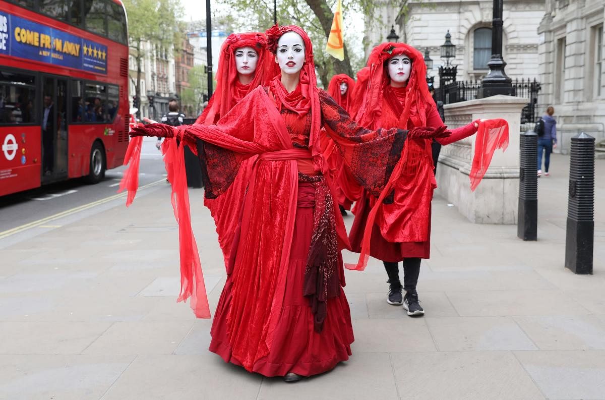 Extinction Rebellion climate change activists in red costume walk along Whitehall in Westminster, London on April 23, 2019. (Photo by ISABEL INFANTES / AFP)