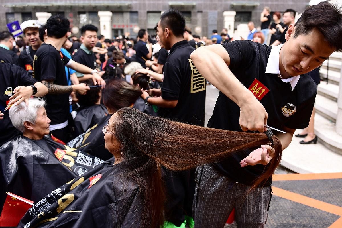 Some 1,400 hairdressers give haircuts as they attempt a Guinness world record for the largest number of people cutting hair at the same time in China. AFP Photo