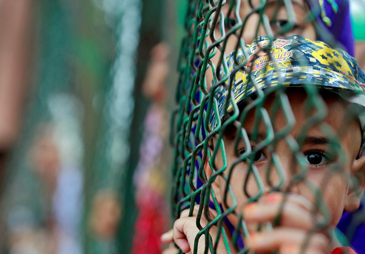 Kashmiri child looks from behind a fence at a protest site after Friday prayers in Srinagar, on August 16, 2019. (REUTERS/Danish Ismail)