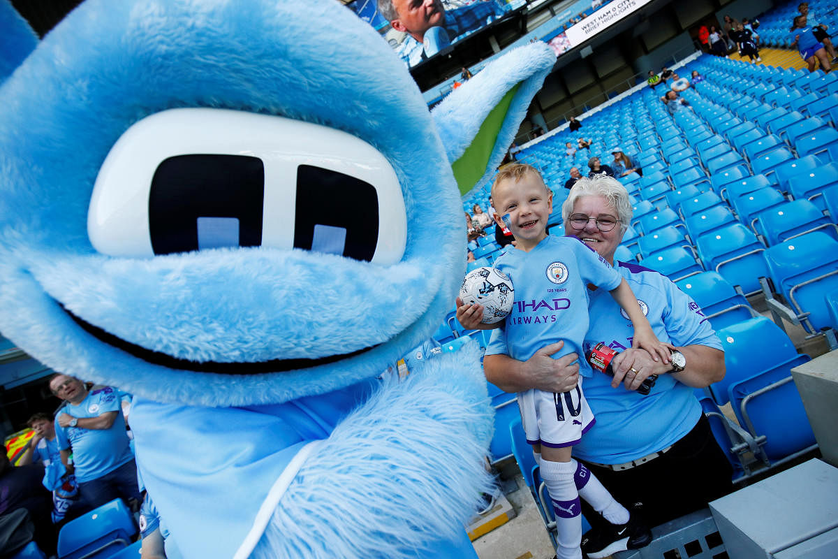  Manchester City fans pose for a photo with the club mascot before the match. (Reuters Photo)