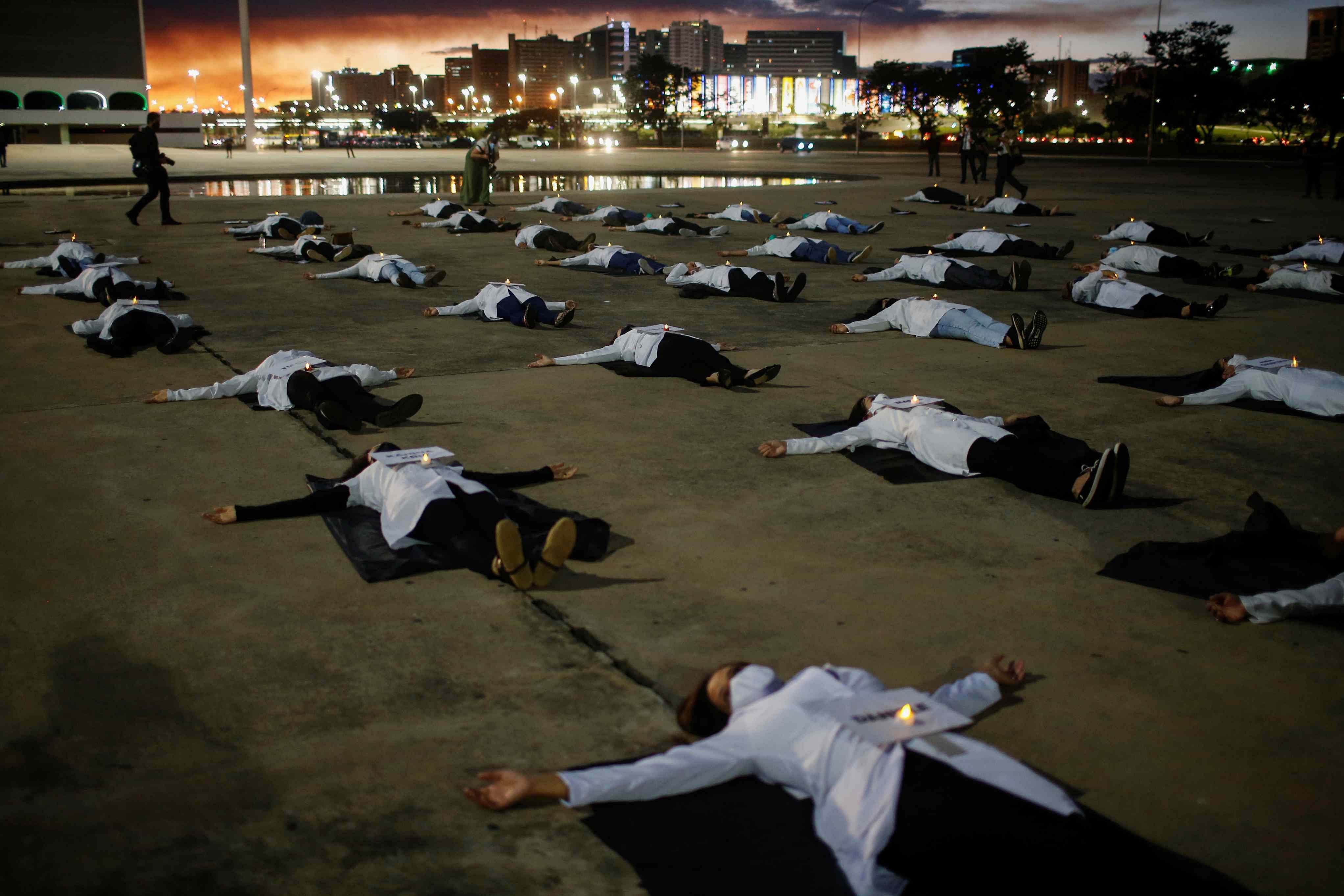 Nurses wearing protective face masks lie on the ground with signs bearing the names of healthcare professionals who died from the coronavirus disease (COVID-19) during a protest amid the COVID-19 outbreak in Brasilia, Brazil (Reuters)