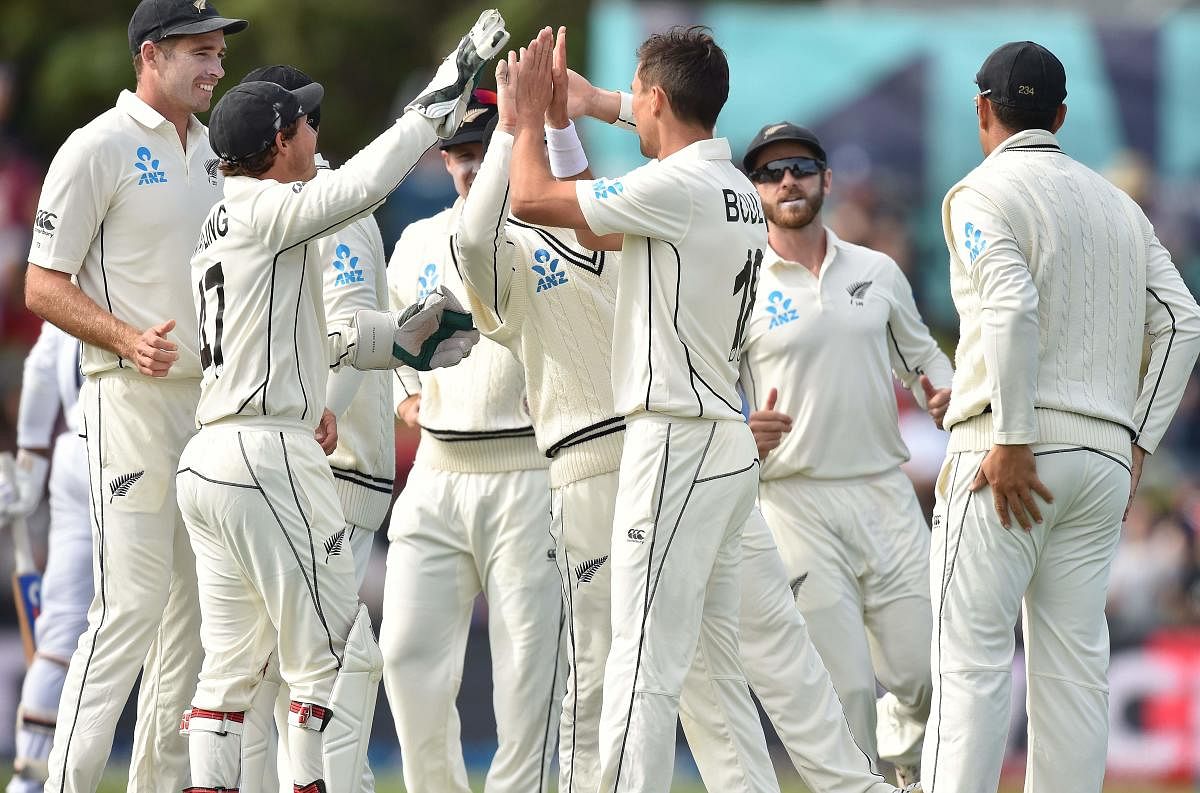 New Zealand bowler Trent Boult (C) is congratulated by teammates after taking the wicket of India's Mayank Agarwal (not pictured) on day two of the second Test cricket match between New Zealand and India at the Hagley Oval in Christchurch on March 1, 2020. (Photo by PETER PARKS / AFP)