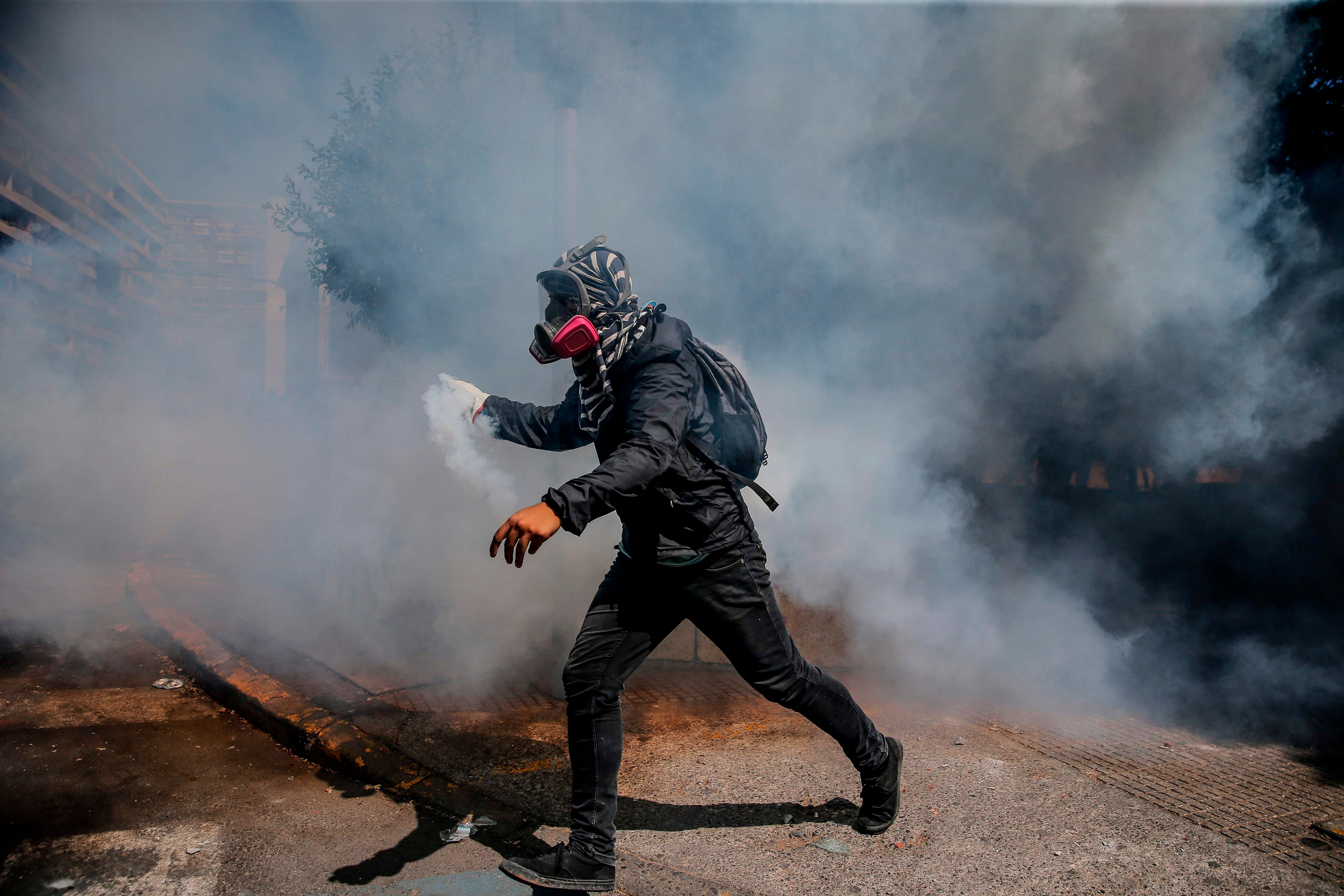 A person holds a tear gas canister during clashes with riot police which erupted during a march on International Women's Day, in Santiago. (Credit: AFP)