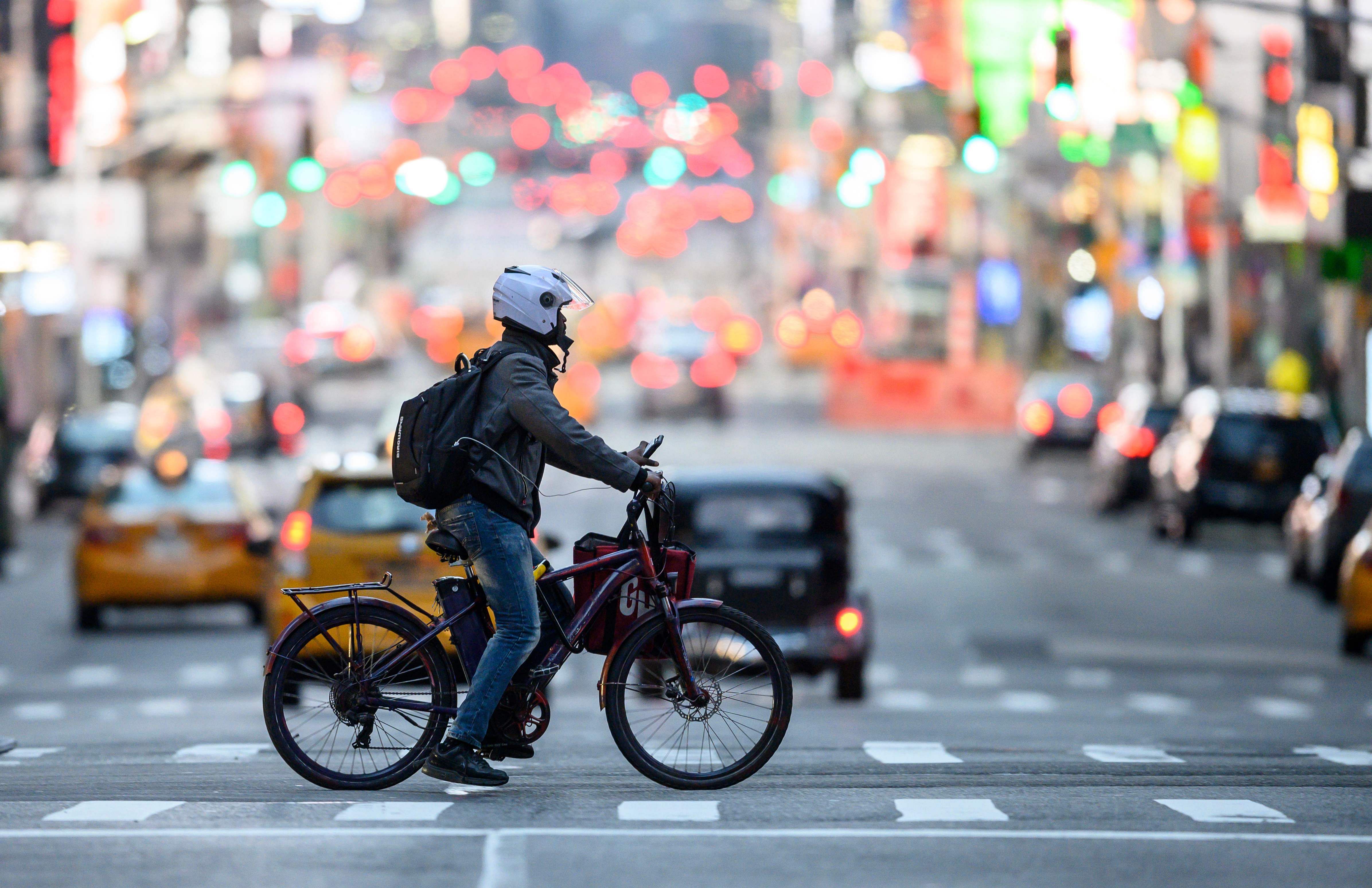 A food delivery man crosses the street in Times Square in Manhattan. (Credit: AFP)