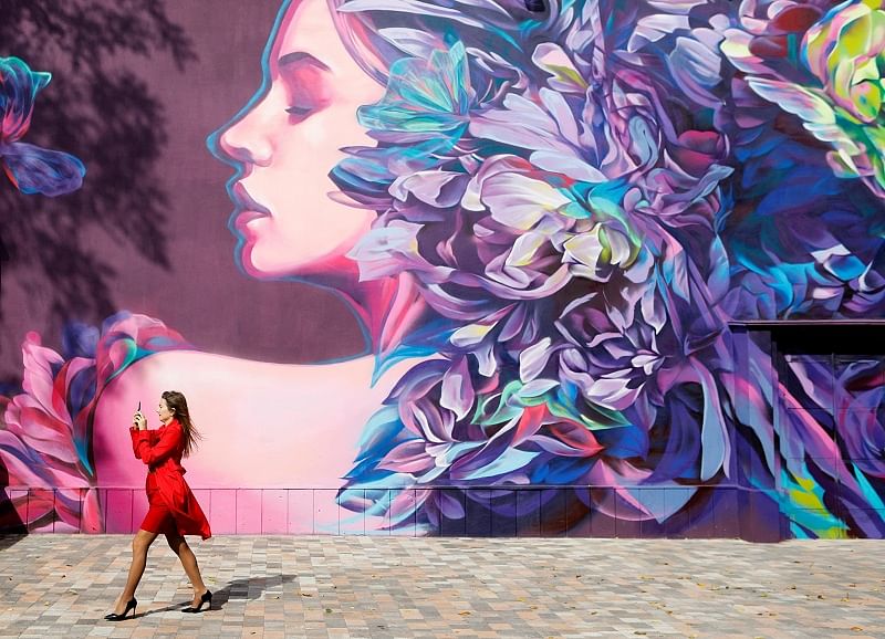 A woman takes pictures in front of a graffiti in central Stavropol, Russia. (Reuters)
