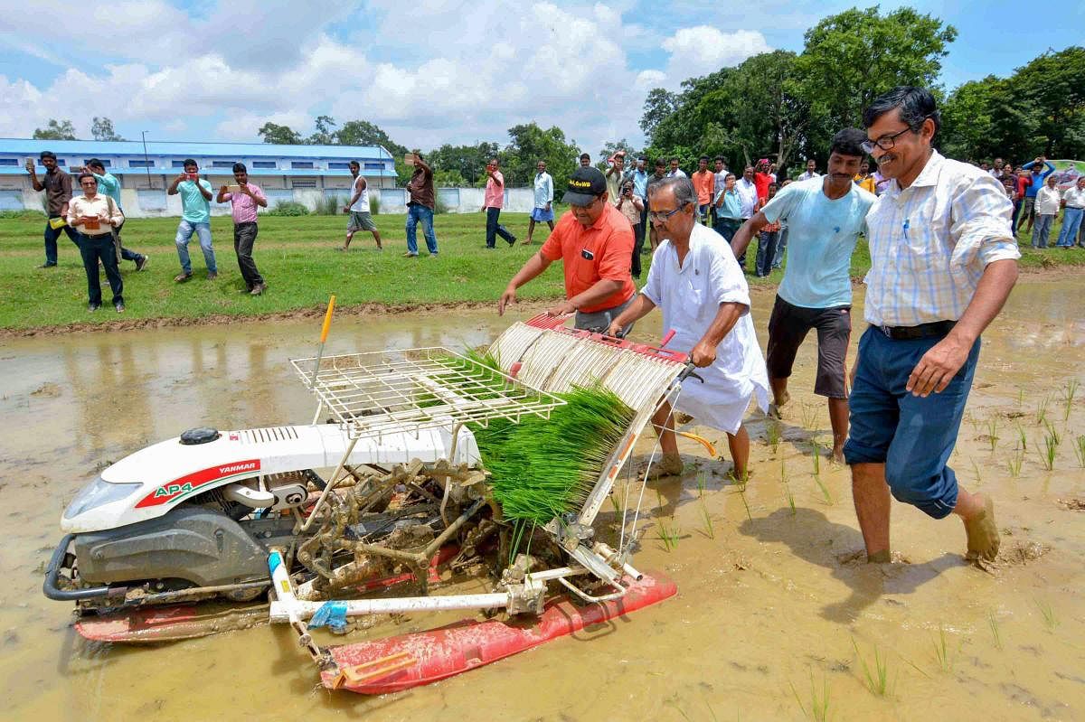 West Bengal Agriculture Minister Asish Banerjee(C) plants paddy saplings in a field with the help of mechanical paddy transplantation at State Agricultural Farm, Suri in Birbhum on Saturday. PTI photo