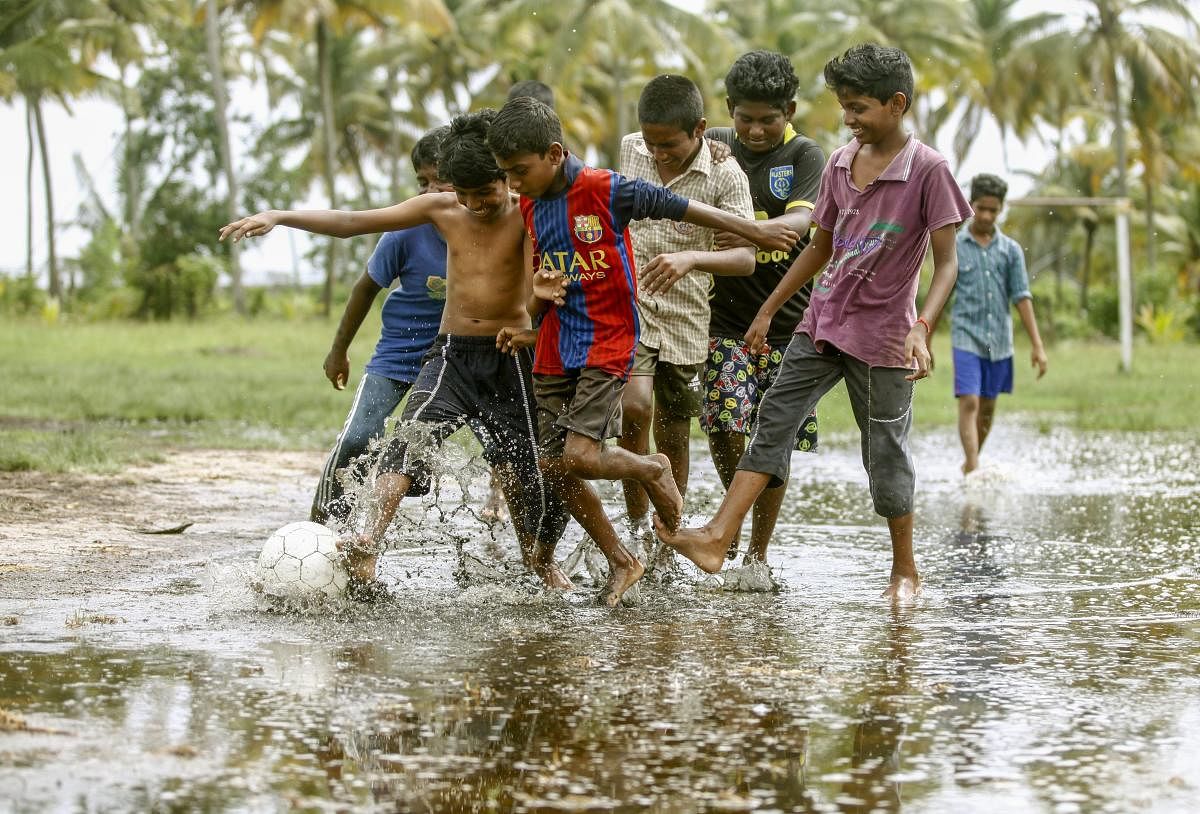 Children play football in the rain water at the coast of Vembanadu Backwater, ahead of the FIFA World Cup, at Vechoor in Kottayam district of Kerala on Tuesday. PTI Photo