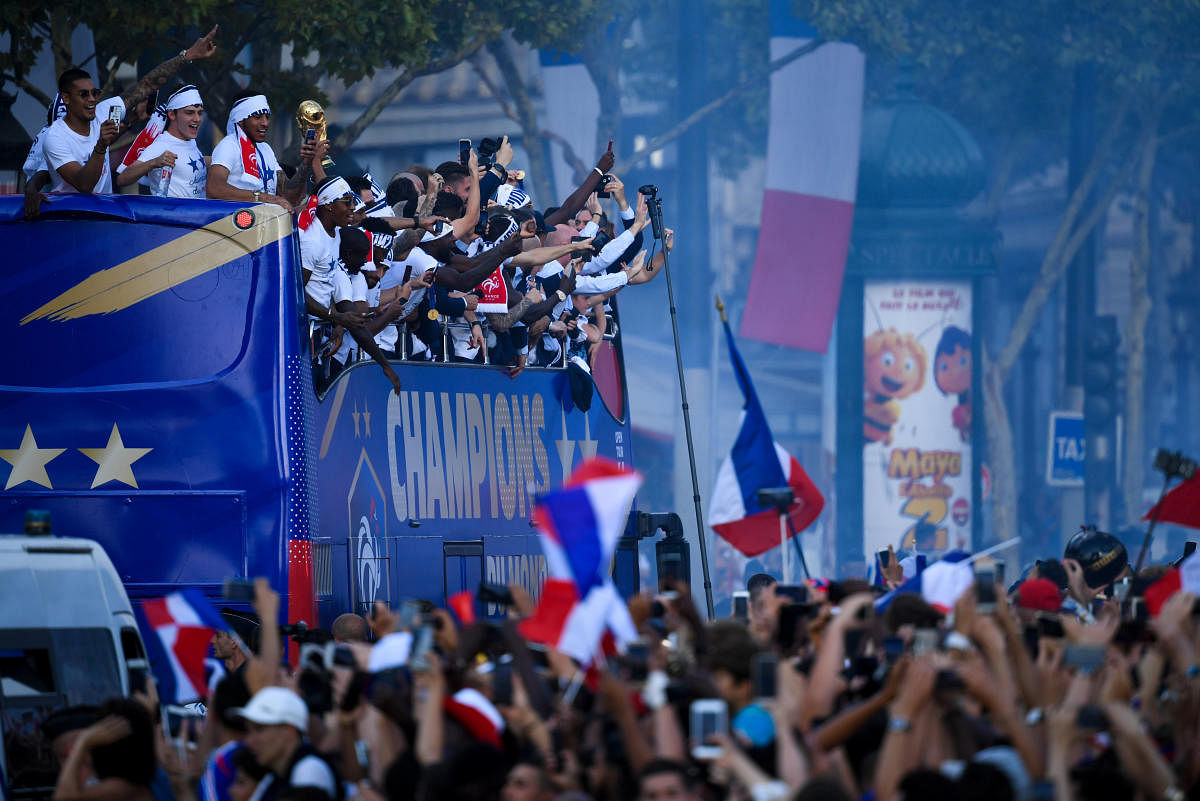 France's fans wave French national flag, light flares and cheer France's team players as they celebrate on the roof of a bus while parading down the Champs-Elysee avenue after winning the Russia 2018 World Cup final football match, in Paris, France July 16, 2018. (Eric Feferberg/Pool via Reuters)