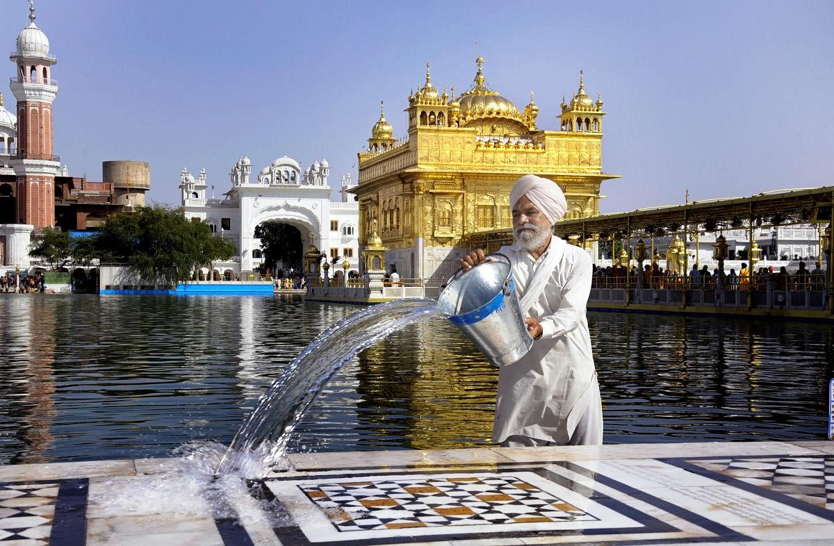  A Sikh volunteer pours water on the marble floor surrounding Harmandir Sahib (Golden Temple) to keep it cool on a hot, summer day in Amritsar on Thursday. PTI Photo 