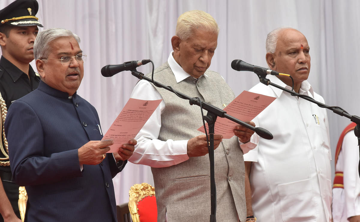 Govind Makthappa Karajol takes oath as a member of Chief Minister B S Yediyurappa’s cabinet at Raj Bhavan in Bengaluru on Tuesday. Governor Vajubhai Vala and B S Yediyurappa are also seen. (DH Photo/Janardhan B K)