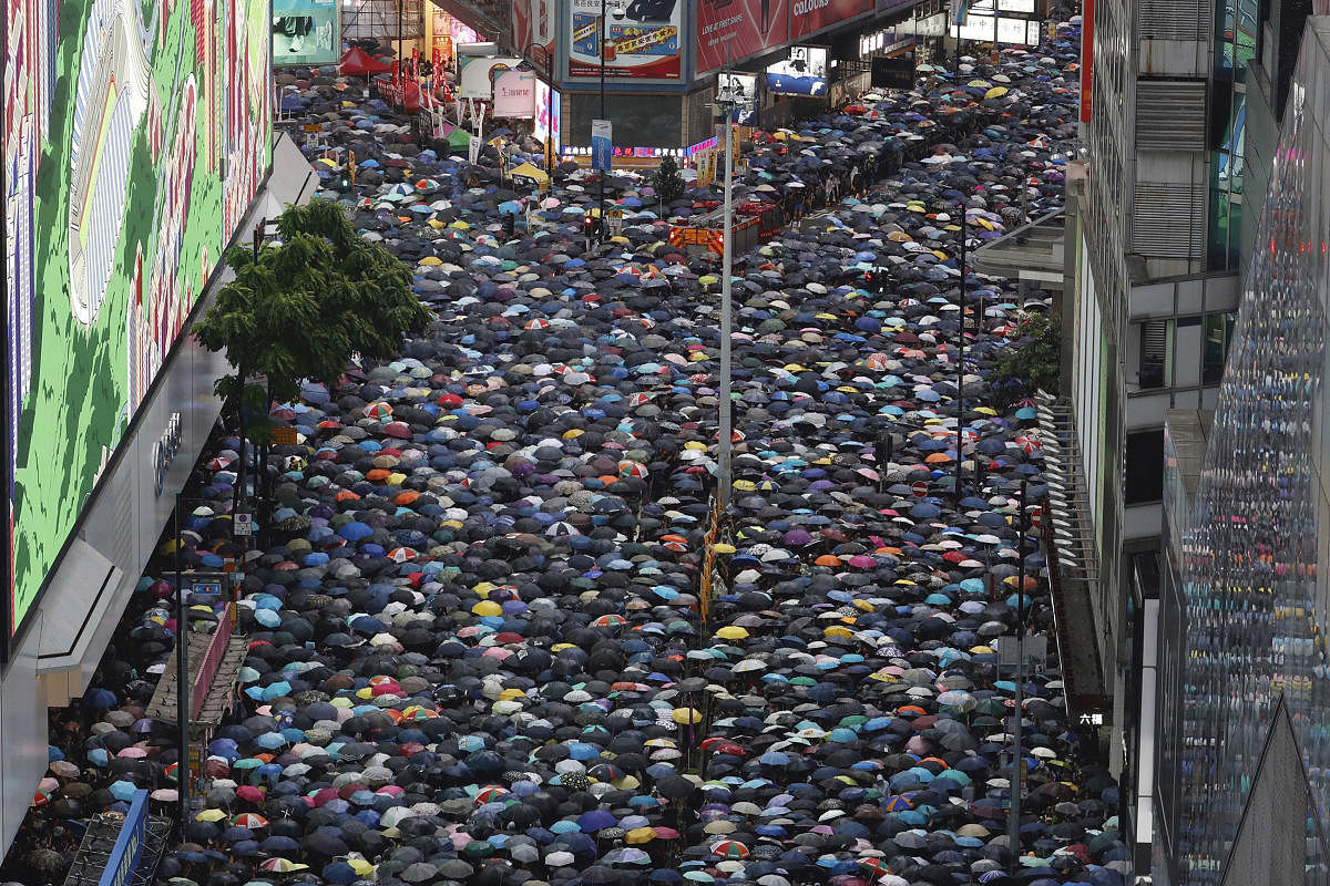 Demonstrators carry umbrellas as they march along a street in Hong Kong, Sunday, Aug. 18, 2019. Heavy rain fell on tens of thousands of umbrella-ready protesters Sunday as they started marching from a packed park in central Hong Kong, where mass pro-democracy demonstrations have become a regular weekend activity. AP/PTI
