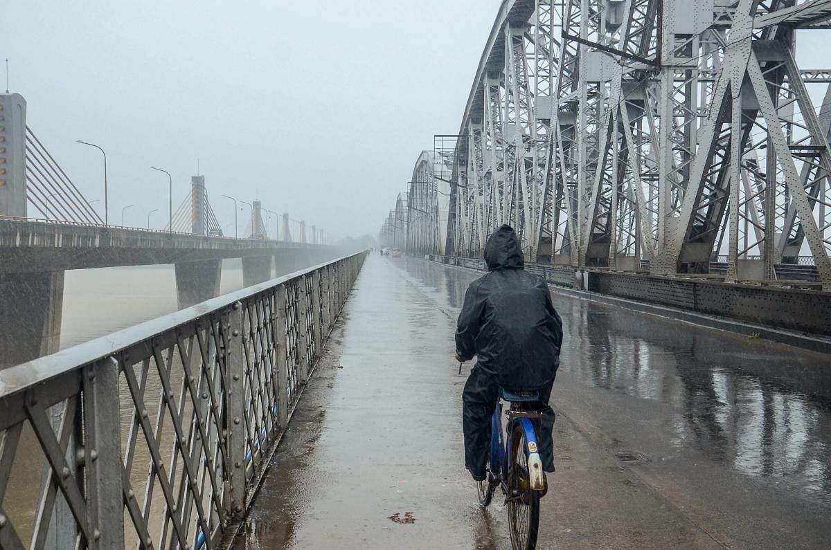 Kolkata: A cyclist rides at Vivekananda Setu during monsoon rainfall, in Kolkata on Wednesday, August 1, 2018. (PTI Photo)