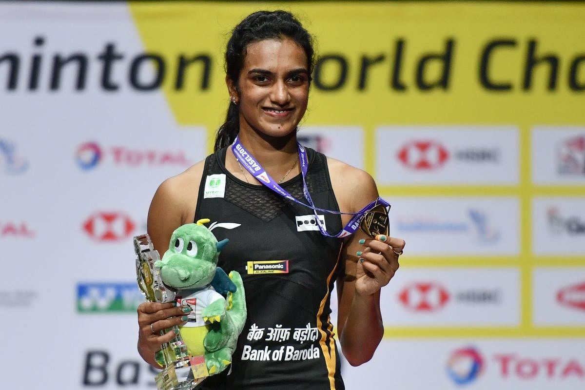 India's PV Sindhu poses with the gold medal during the podium cermony after her victory over Japan's Nozomi Okuhara during their women's singles final match at the BWF Badminton World Championships at the St Jakobshalle in Basel on August 25, 2019. (Photo by FABRICE COFFRINI / AFP)