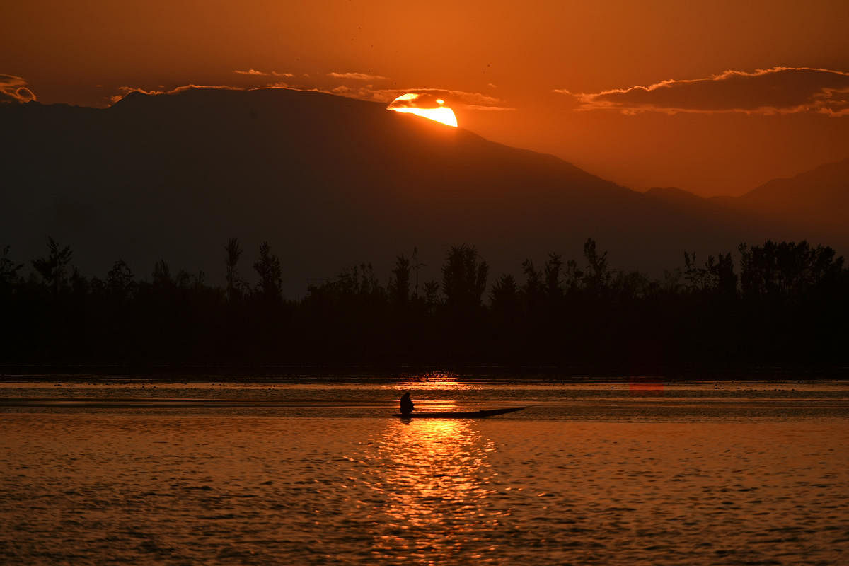 A boatman rides a boat at sunset in Dal lake during a government-imposed nationwide lockdown as a preventive measure against the COVID-19 coronavirus, in Srinagar on April 21, 2020. (Photo by AFP)