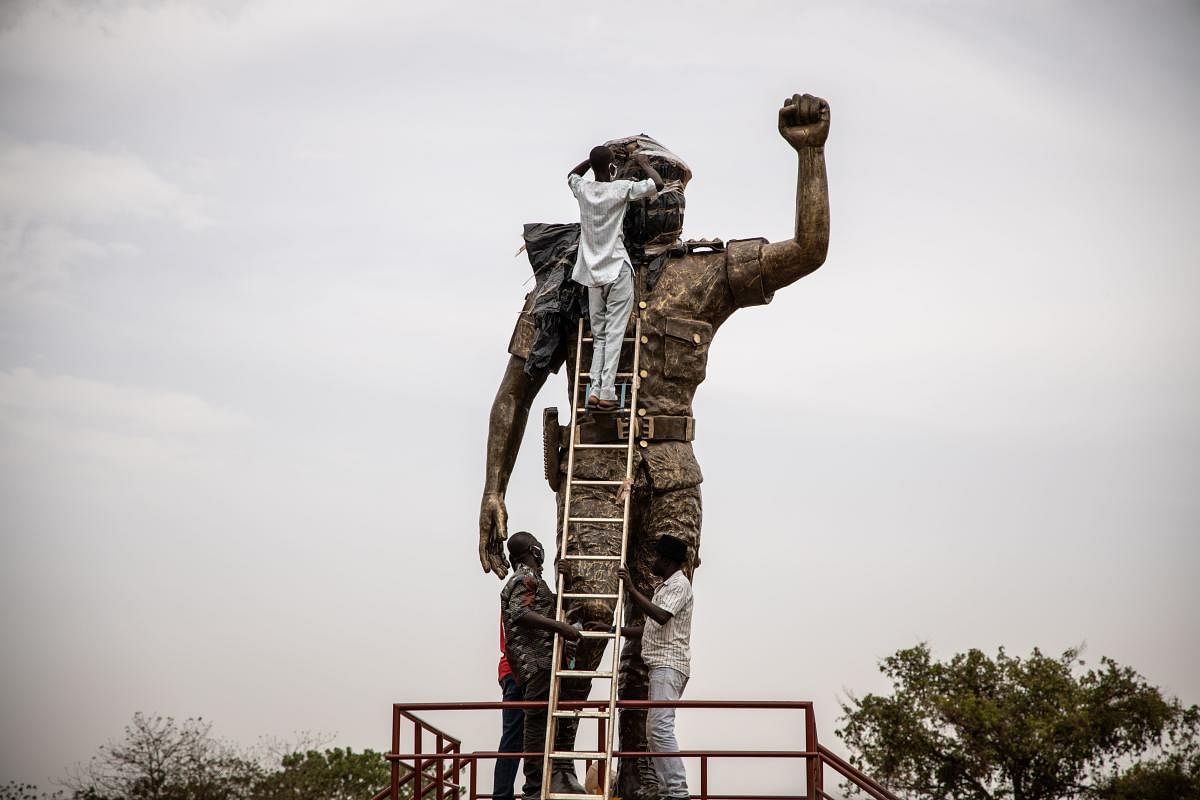 Employees unveil the second bronze statue of Burkina Faso's former President Thomas Sankara who was killed on October 15, 1987, at his memorial at the Conseil de l'Entente in Ouagadougou, on May 17, 2020. (AFP Photo)