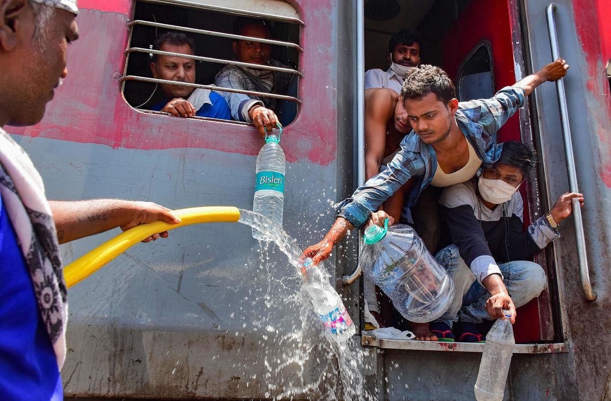 A railway employee refills water bottles of migrants sitting in a train to reach their native places, during the ongoing COVID-19 lockdown, in Jabalpur, Tuesday, May 26, 2020. (PTI Photo)