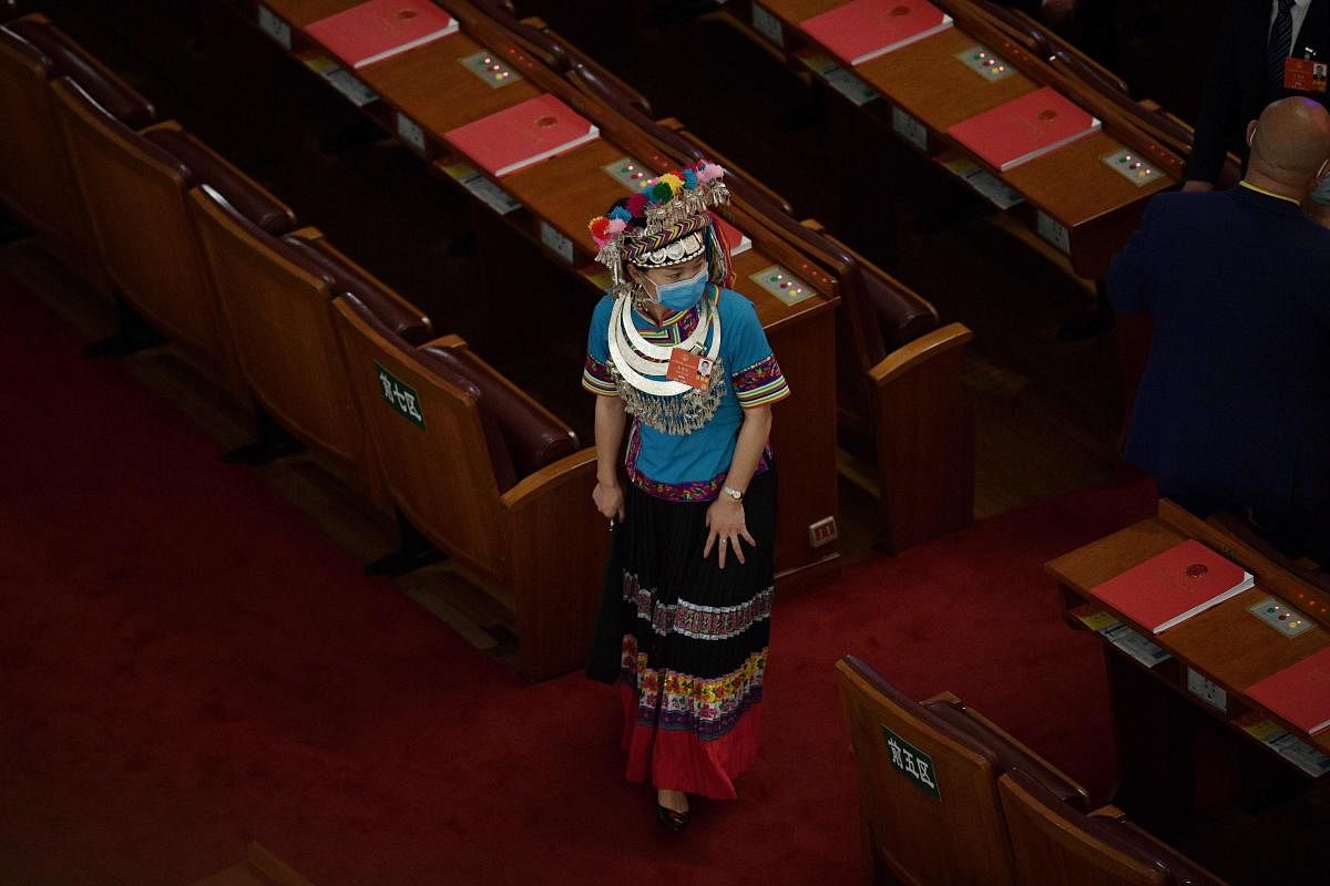 An ethnic minority delegate prepares to take her seat before the closing session of the National People's Congress at the Great Hall of the People in Beijing. AFP