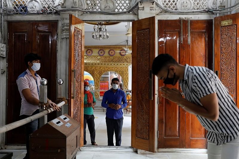 Men wearing protective masks wait to pray as they maintain social distancing inside a temple after the opening of most of the religious places after India eases lockdown restrictions that were imposed to slow the spread of the coronavirus disease (COVID-19), in New Delhi. Credit: Reuters Photo