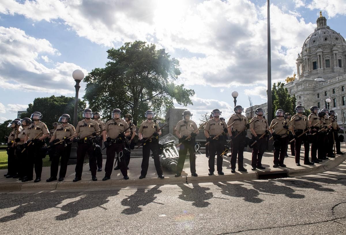 Members of the Minnesota State Patrol stand guard over a statue of Christopher Columbus which was toppled to the ground by protesters on the grounds of the State Capitol. Credit/AFP Photo