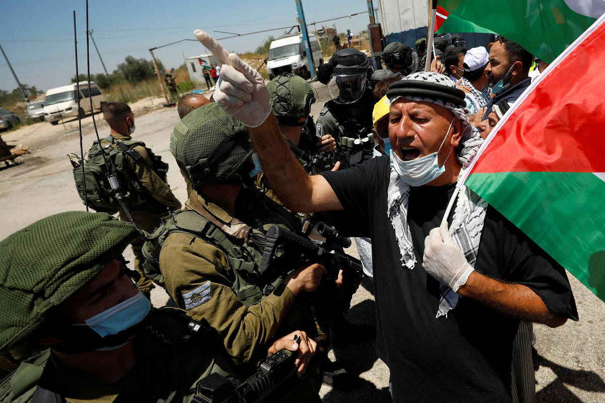 A demonstrator holding a Palestinian flag gestures in front of Israeli forces during a protest against Israel's plan to annex parts of the occupied West Bank, in Haris June 26, 2020. CRedit/Reuters Photo