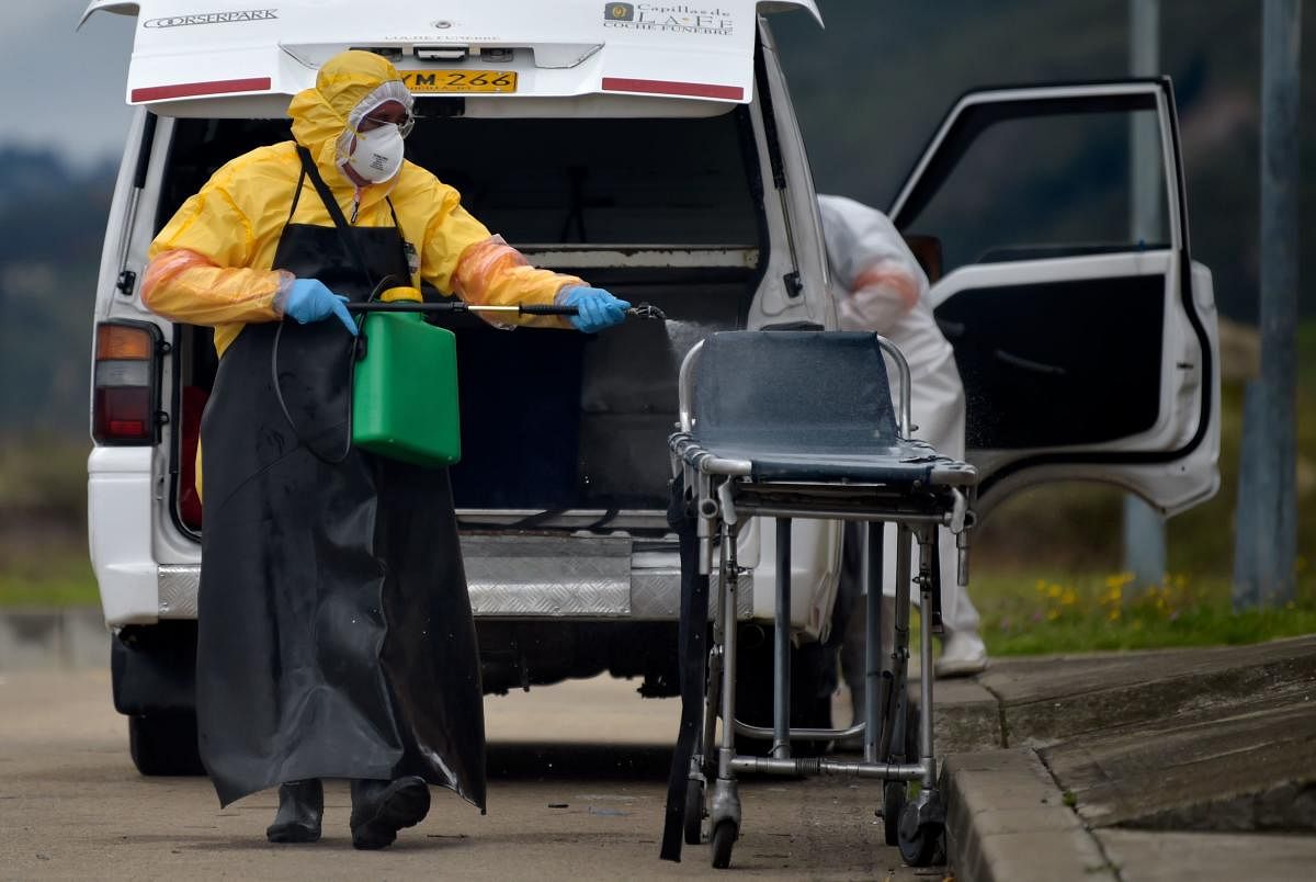 A worker disinfects a stretcher after moving the coffin of a Covid-19 victim to be cremated at Serafin cemetery in Bogota. Credit: AFP