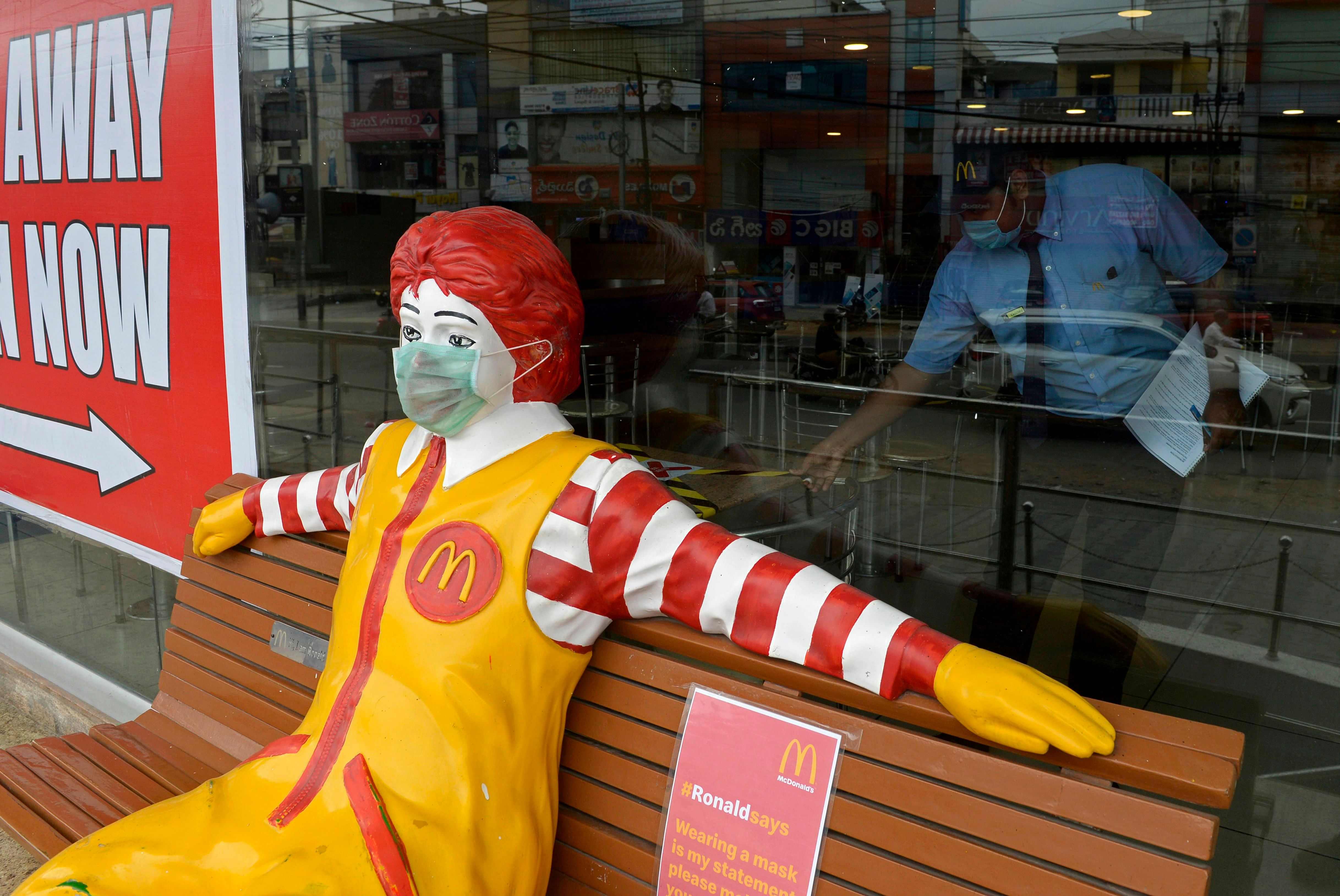 A face mask is seen on Ronald McDonald, the mascot of fast-food company McDonald's, as an employee works inside its outlet after the authorities eased restrictions imposed as a preventive measure against the spread of the COVID-19 in Hyderabad. Credits: AFP Photo