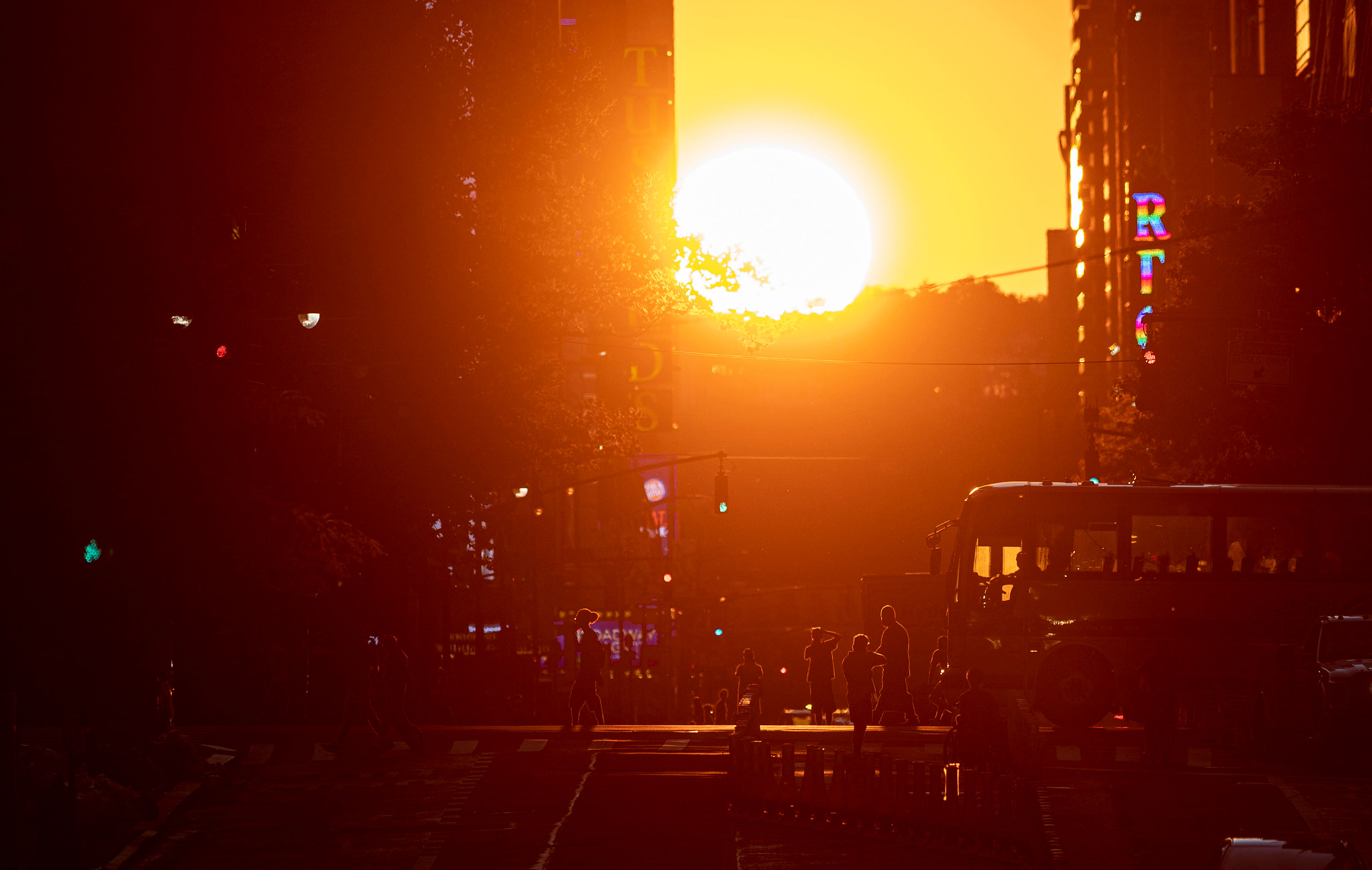 The sun sets along 42nd Street, during the so called "Manhattanhenge", on July 13, 2020 in New York City. - The so called Manhattanhenge happens four times each year, when when the sun rises or sets in New York City parallel to the city street grid in Manhattan. Credit: AFP
