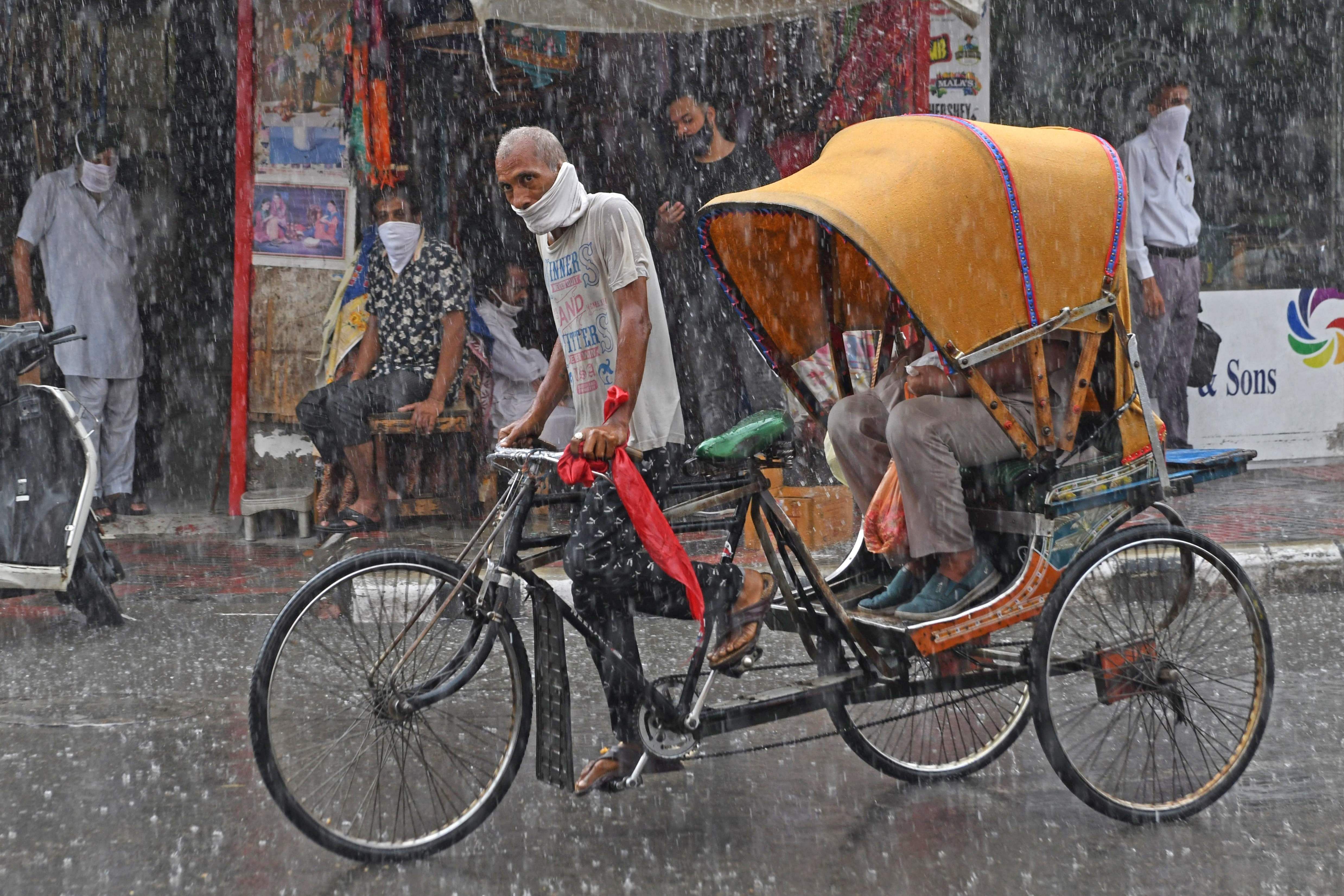 A rickshaw rider makes his way through a heavy rain shower in Amritsar on July 16, 2020. Credit: AFP