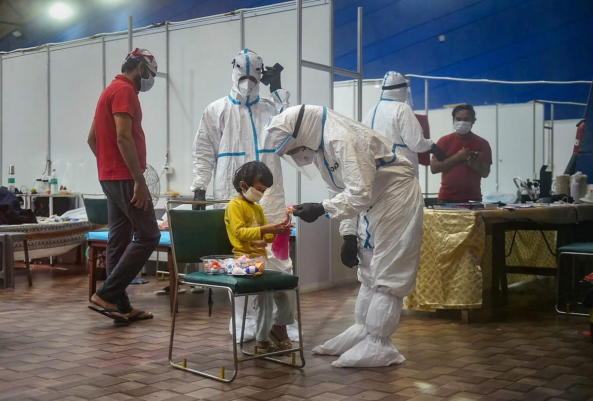 A medic plays with a child Covid-patient at CWG Village Covid-19 Care Centre, near Akshardham in New Delhi. Credit: PTI