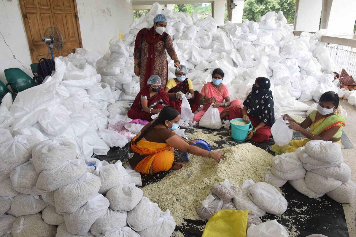 Volunteers make relief food packets for flood-affected people, at SKM hall in Patna amid lockdown. Credit: PTI