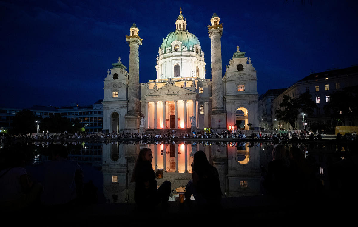 People sit outside Karlskirche (Church of St. Charles) where Popfest is taking place, amid the coronavirus disease outbreak in Vienna, Austria. Credit: Reuters