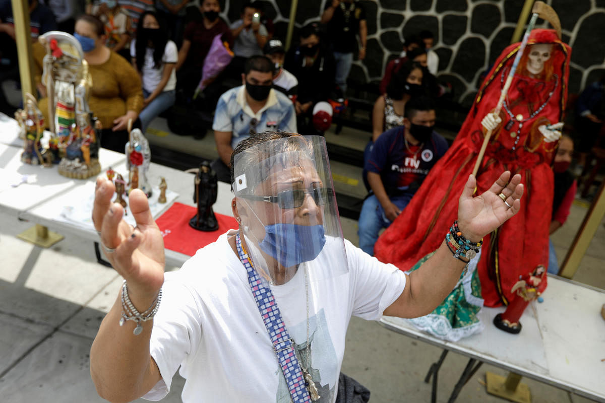 A man wearing protective face mask and face shield prays during a mass on the first day of the reopening of the temple of the cult figure La Santa Muerte (The Saint of Death) after government restrictions were eased, amid the coronavirus disease (COVID-19) outbreak in Tultitlan, on the outsides of Mexico City, Mexico. Credit/Reuters Photo