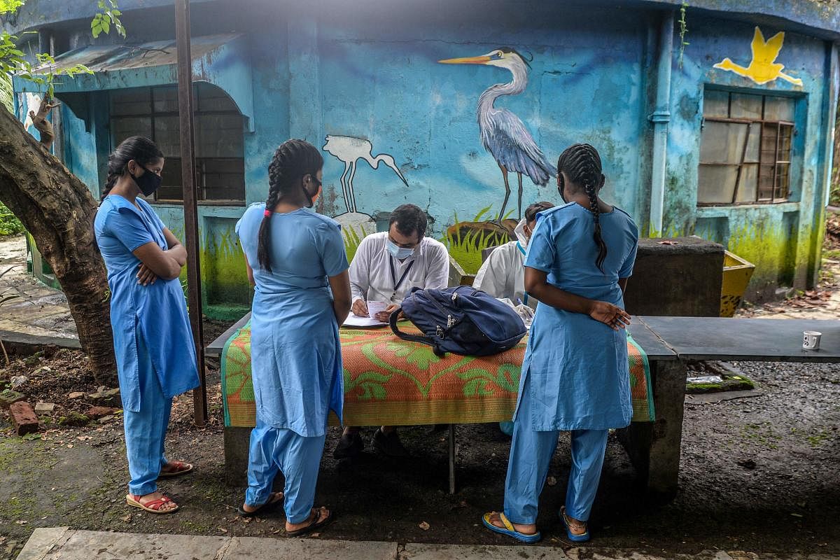 Health workers (sitting) write down details of students at the Children Aid Society premises during a medical screening for coronavirus. Credit: AFP