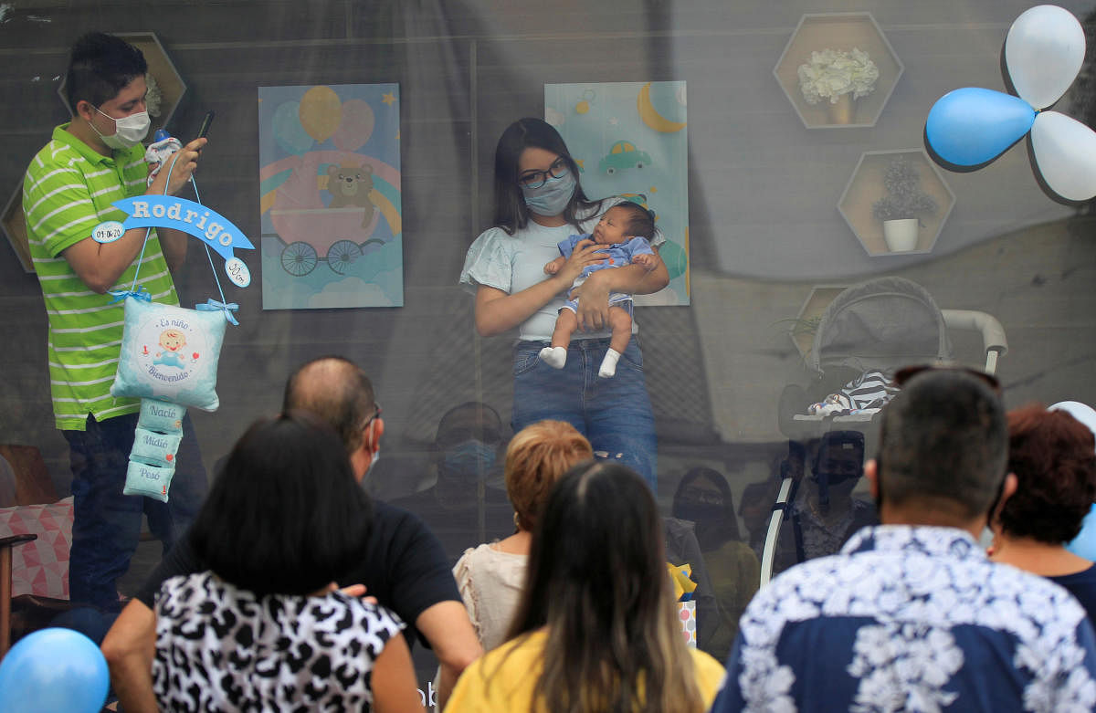 A couple is seen with their newborn baby inside a sanitized cabin called "Baby Cabin Parade" to show the newborn to relatives as a social distancing solution during the coronavirus outbreak in Monterrey, Mexico. Credit: Reuters
