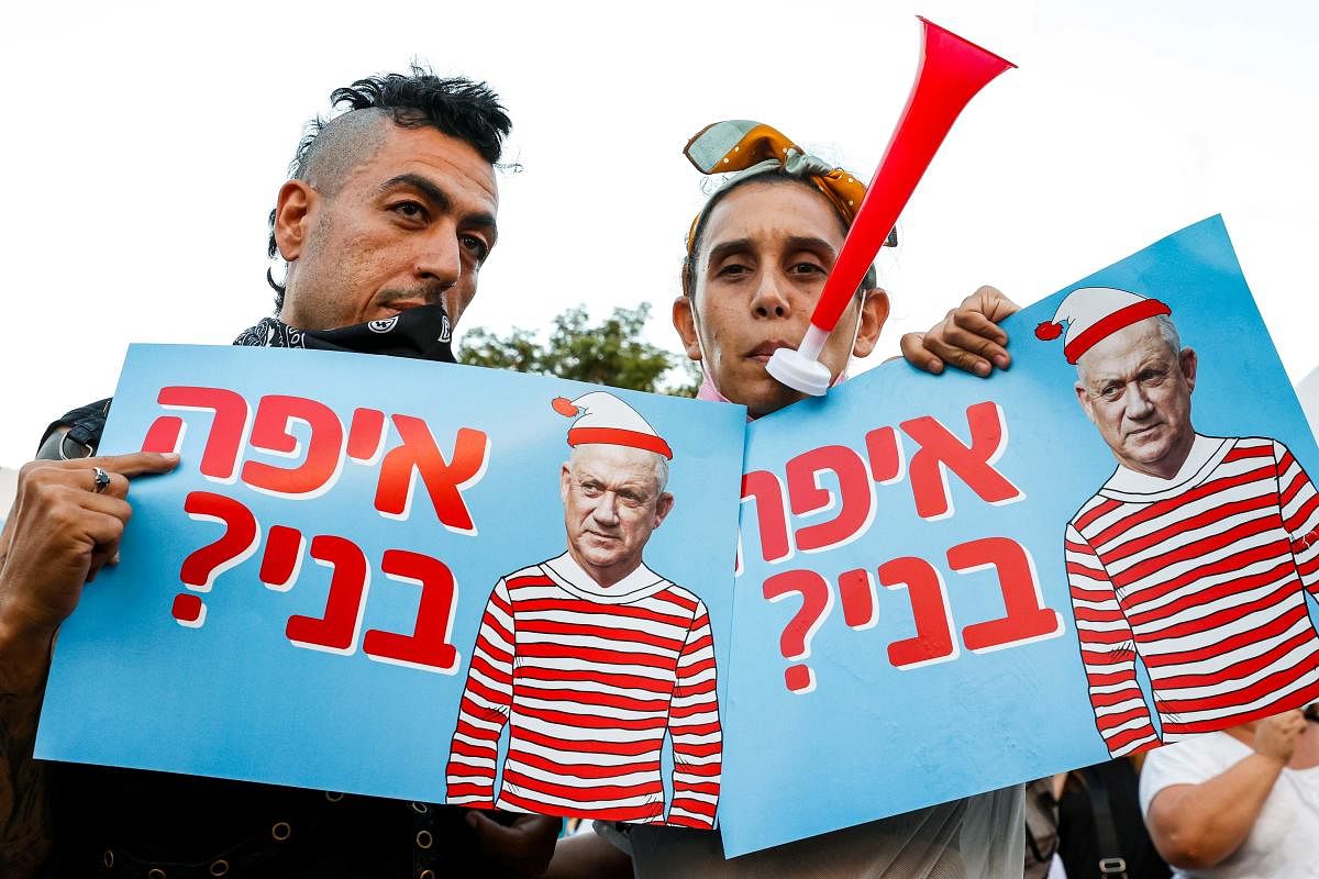 Protesters stand holding sign depicting Benny Gantz, Israel's alternate prime minister and defence minister, as Waldo or Wally from the children's puzzle book series with text in Hebrew reading "where's Benny?" during a demonstration against Gantz near his house in the Israeli city of Rosh Ha-Ayin. Protesters accuse Gantz of staying in government with Netanyahu and discrediting people who voted for him. AFP