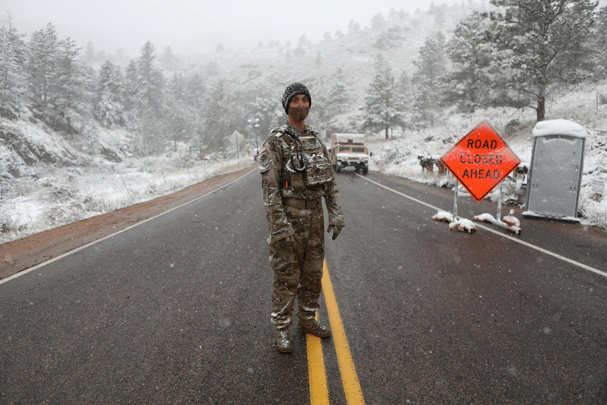 Colorado National Guard members monitor a roadblock leading to the Cameron Peak wildfire as snow falls a day after the region sweltered through temperatures in the 90s Fahrenheit (32 degrees Celsius) outside Fort Collins, Colorado, US. Credit: Reuters Photo