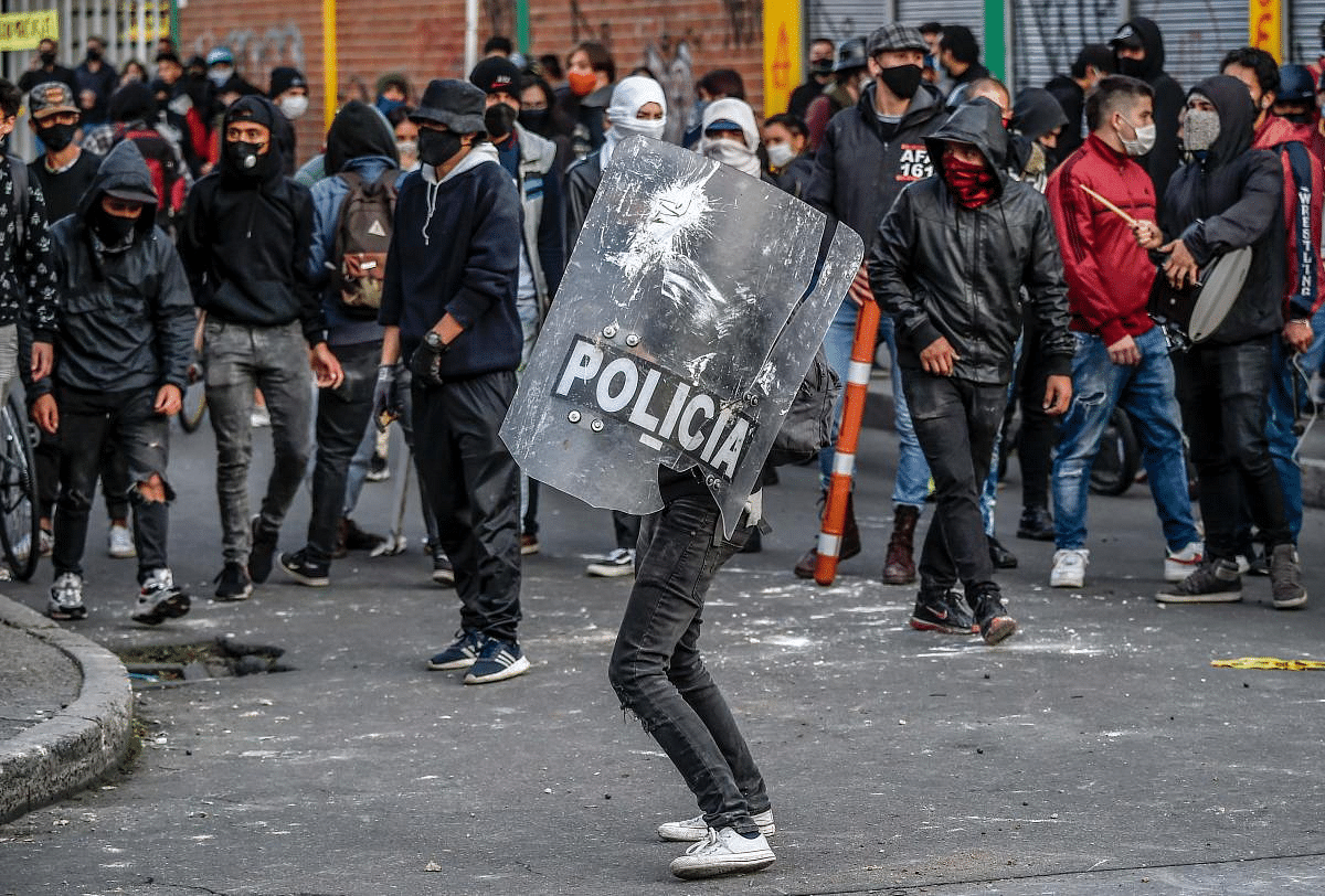A demonstrator holds a police shield during a protest against the death of a lawyer under police custody, in Bogota. - A man who was detained by police officers died Wednesday in Bogota after receiving repeated electric shocks on the ground with a stun gun. Credit: AFP Photo