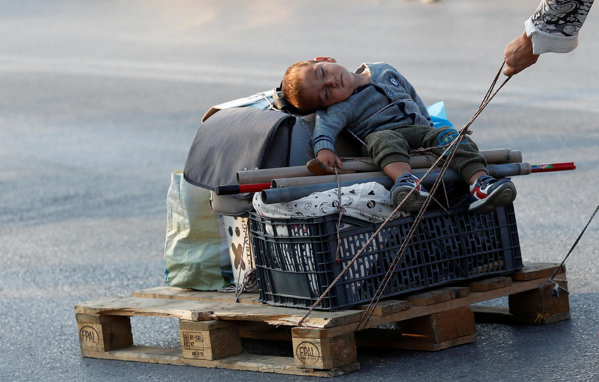 A woman pulls a baby on a pallet as they prepare to move to a new temporary camp for migrants and refugees, on the island of Lesbos, Greece. Credit: Reuters Photo