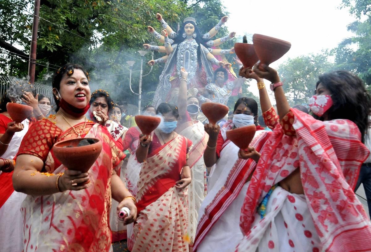 Women perform 'Dhunachi' dance on the arrival procession of Goddess Durga idol at their community puja pandal ahead of 'Durga Puja' festival, amid coronavirus pandemic, in Kolkata.