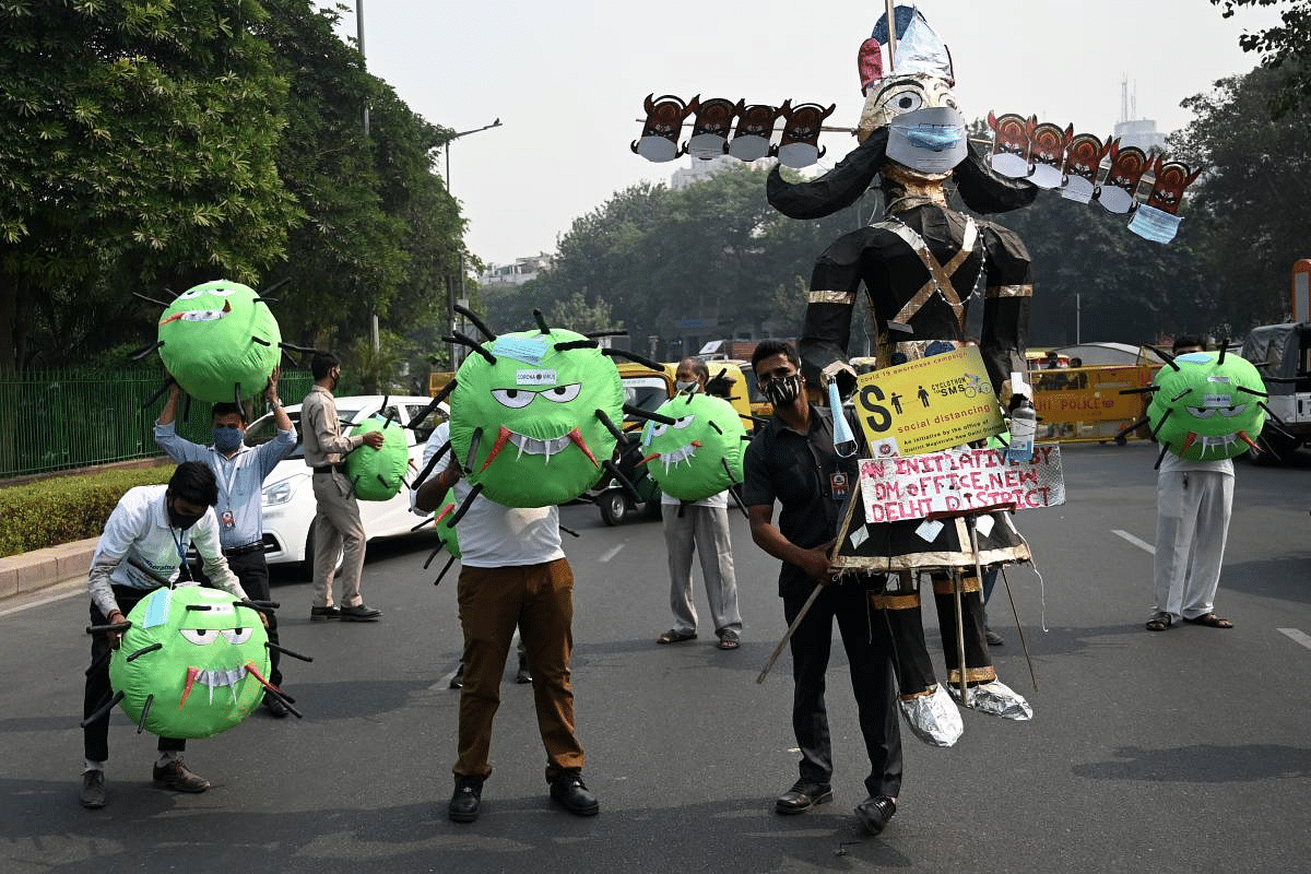Officers from the district magistrate office hold Covid-19 coronavirus-themed mascots and an effigy of Hindu demon King Ravana on a road during an awareness campaign against coronavirus and rising air pollution levels in New Delhi. Credit: AFP Photo