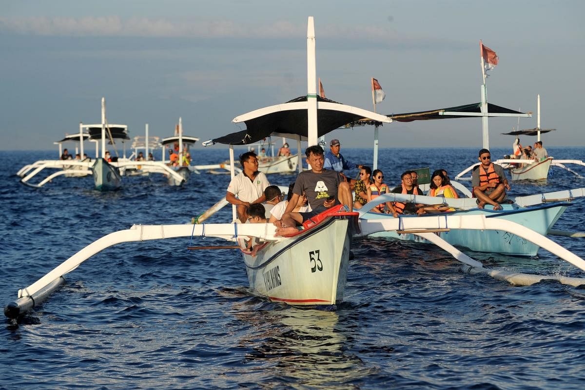 Tourists ride traditional boats during a dolphin-watching excursion at sunrise in the waters off Lovina Beach on Bali island's Singaraja regency. Credit: AFP.