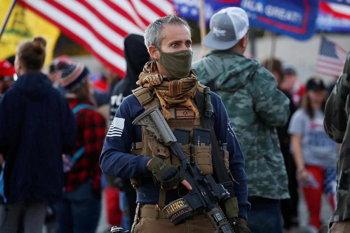 A supporter of US President Donald Trump carries a semi-automatic rifle as he takes part in a "Stop the Steal" protest after the 2020 US presidential election was called for former Vice President Joe Biden, in front of the Maricopa County Tabulation and Election Center (MCTEC), in Phoenix, Arizona, US. Credit: Reuters Photo