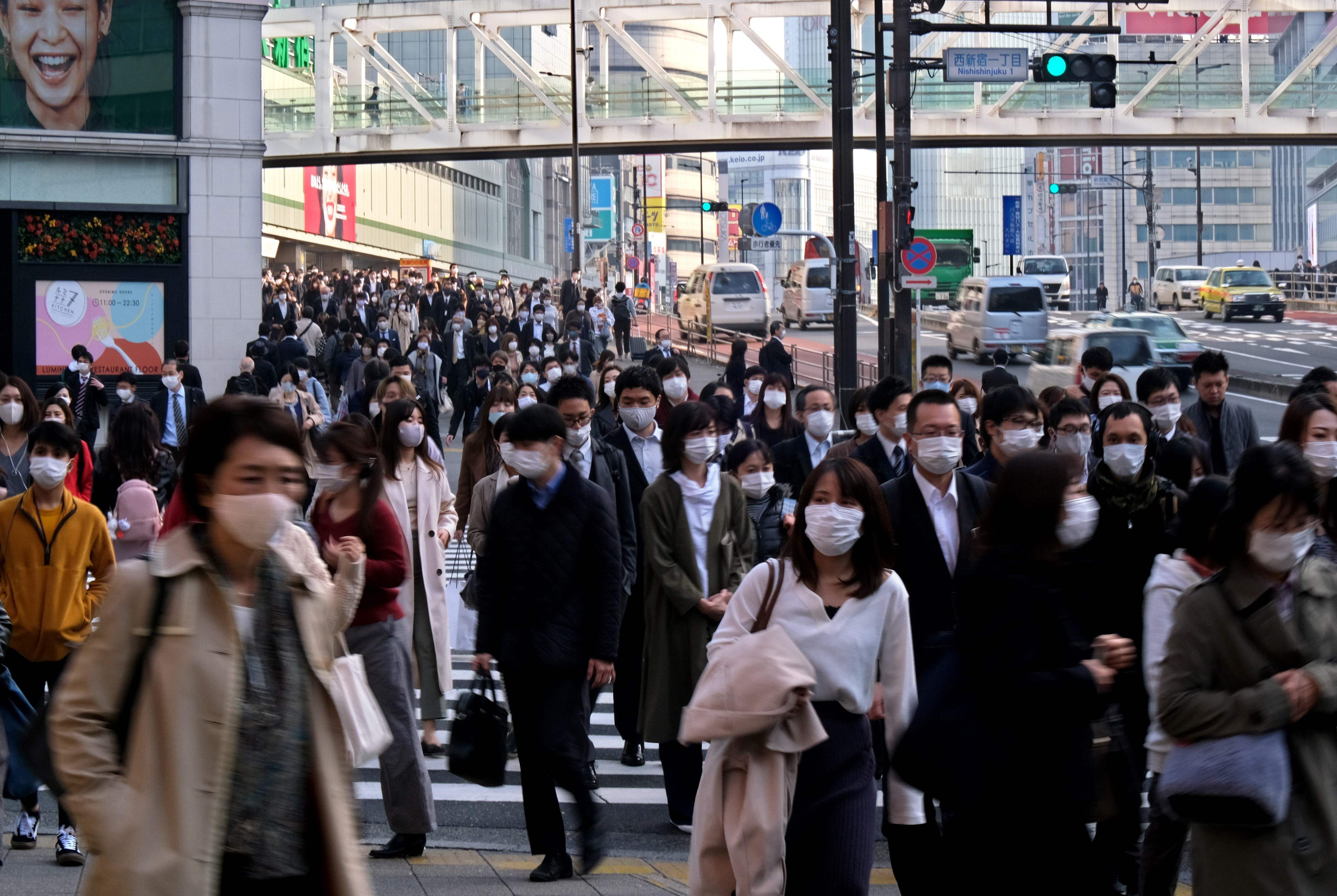 Commuters wearing masks walk near Shinjuku Station in Tokyo. Credit: AFP Photo