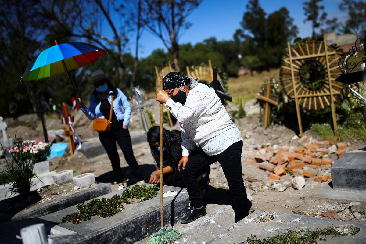 Maru, daughter of Natalia, who died on August of the coronavirus at the age of 86, mourns in front of her grave, as Mexico surpasses 100,000 deaths from the virus, in Mexico City, Mexico. Credit: Reuters Photo