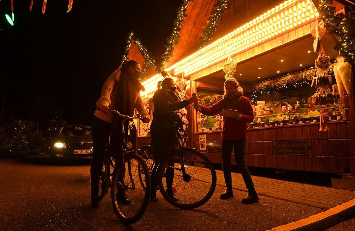 Visitors with bicycles place their orders at the drive in the Christmas market in Landshut, southern Germany. Artificial snow, mulled wine, all-you-can-eat sweets and kitsch music: at the Christmas market in Landshut, southern Germany, the essentials are there, but you have to pick it up by car. Credit: AFP Photo.